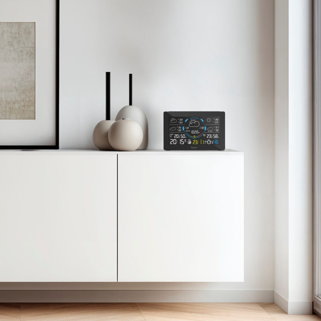 Hama WLAN-Wetterstation mit Farbdisplay auf weißem Sideboard, zeigt Uhrzeit, Temperatur und Wettervorhersage
