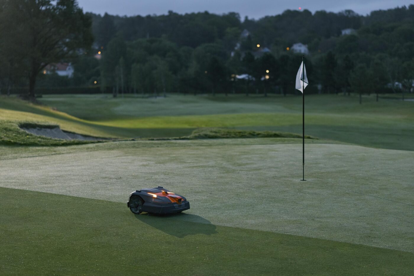 Husqvarna Automower 580L EPOS mäht bei Dämmerung autonom ein Golfplatz-Green neben dem Fahnenstock