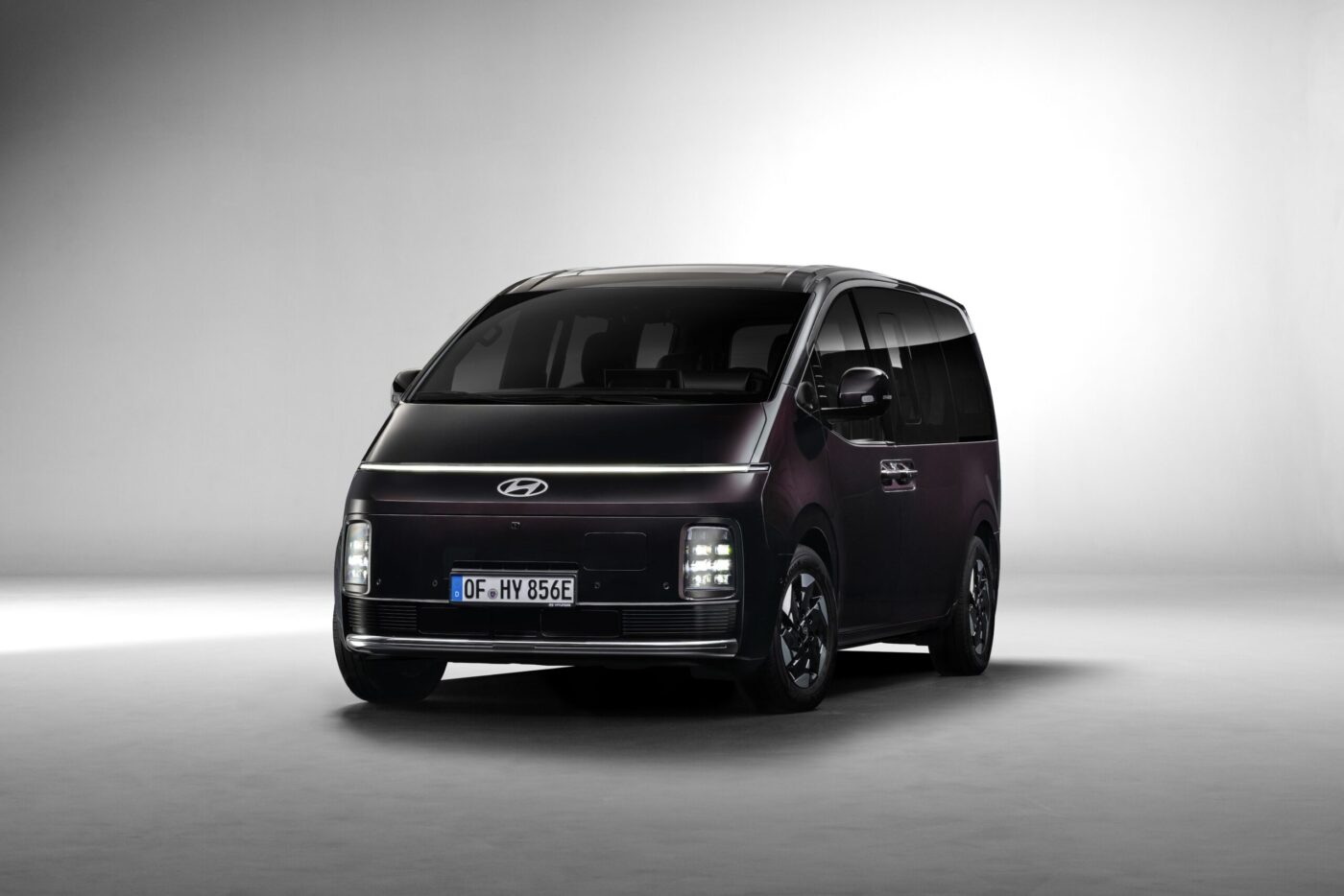 Hyundai STARIA Elektro in Dunkelviolett, Frontansicht im Studio mit blauem E-Kennzeichen