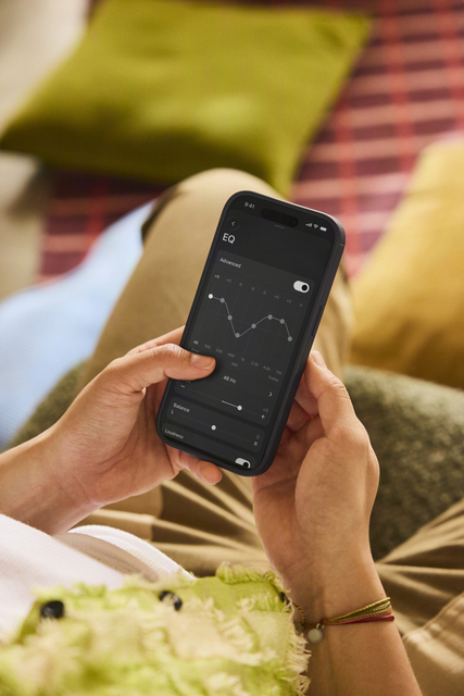 Hände halten iPhone mit Sonos-App geöffnet auf dem EQ-Einstellungsbildschirm