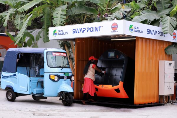 SUN Mobility Swap Point Batteriewechselstation mit Elektro-Tuk-Tuks und Mitarbeiterin an der Wechselmaschine