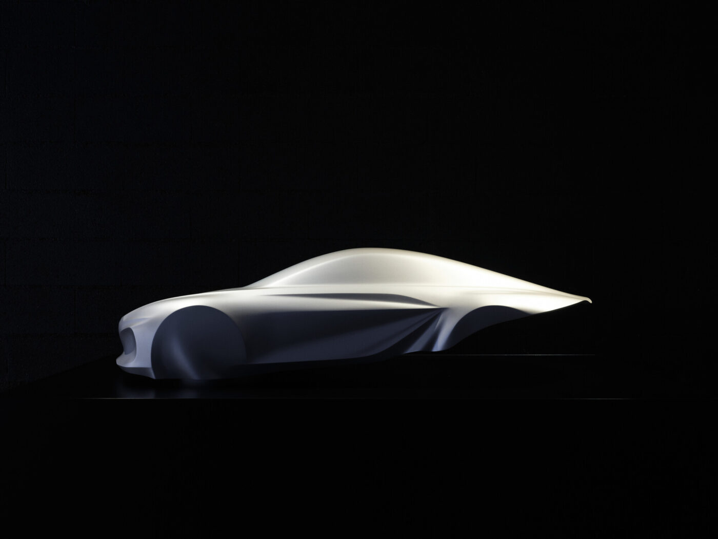 Alpine A110 Gen-3-Designskulptur im Seitenprofil – weißes, fließendes Tonmodell vor schwarzem Hintergrund