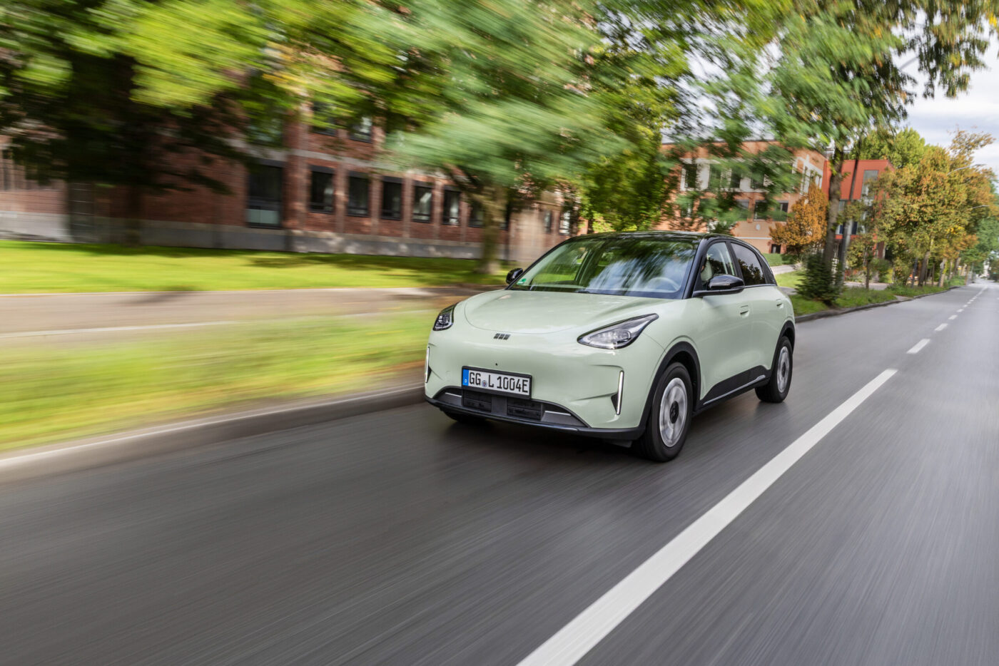 Geely E2 in Mintgrün fährt auf einer Stadtstraße – frontale Dreiviertelansicht