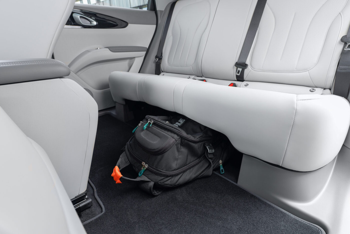Schwarzer Rucksack unter der Rücksitzbank des Geely E2 – helles Lederinterieur