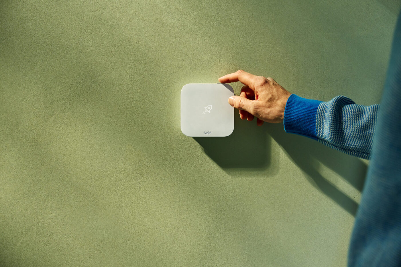 Hand bedient tado° Thermostat X (2. Gen.) an hellgrüner Wand