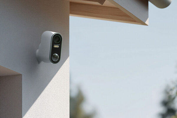 Homematic IP Akku-Außenkamera HmIP-COR an weißer Hausfassade unter Dachvorsprung montiert