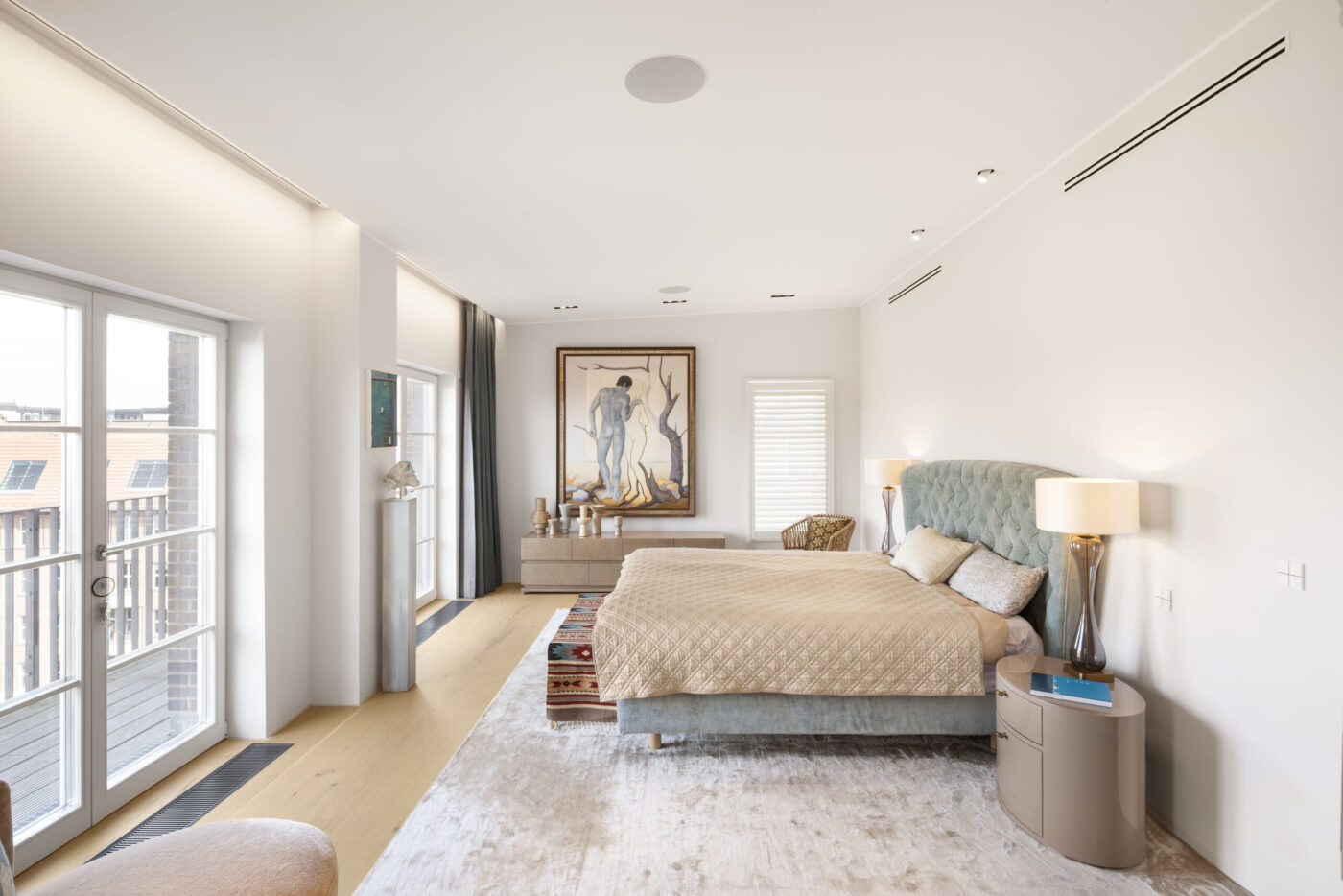 Penthouse-Schlafzimmer mit Deckeneinbaulautsprecher, gepolstertem Bett und Balkon