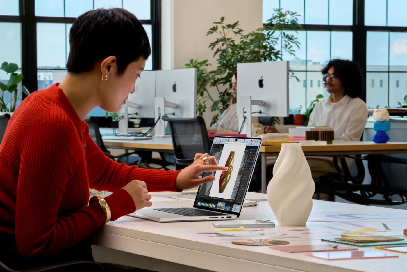 Designerin bedient Touch-Display des Apple MacBook Pro mit M5 im Kreativbüro