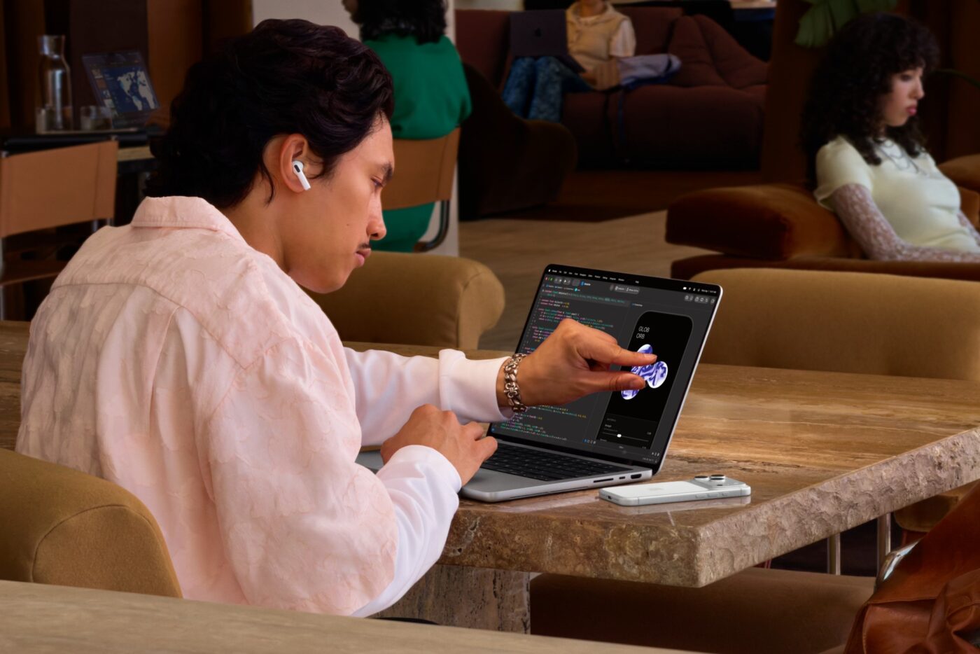 Mann bedient Touchscreen des Apple MacBook Pro mit M5 in einem Café