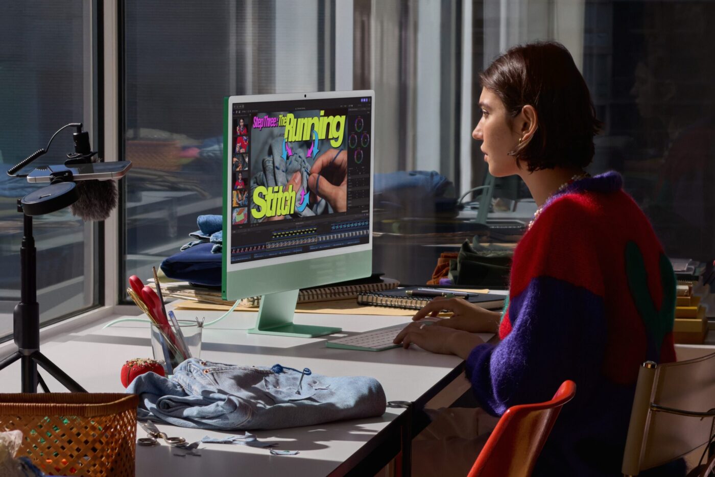 Frau arbeitet an mintgrünem Apple iMac mit M6 in Final Cut Pro an einem Videoprojekt