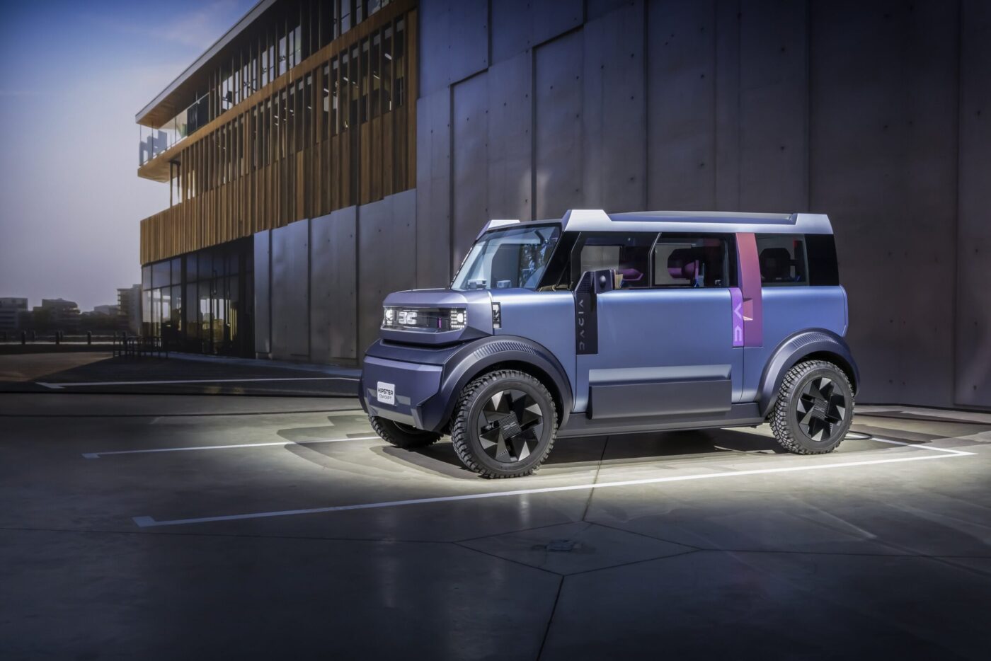 Dacia Hipster Concept, silberblaues L7e-Elektrofahrzeug mit Würfelform, vor modernem Gebäude