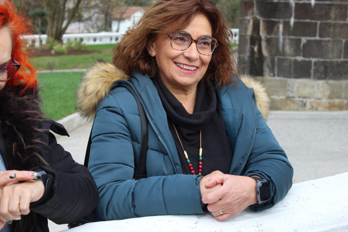 Ältere Frau mit SaveFamily Senior Smartwatch am Handgelenk lächelt entspannt im Freien