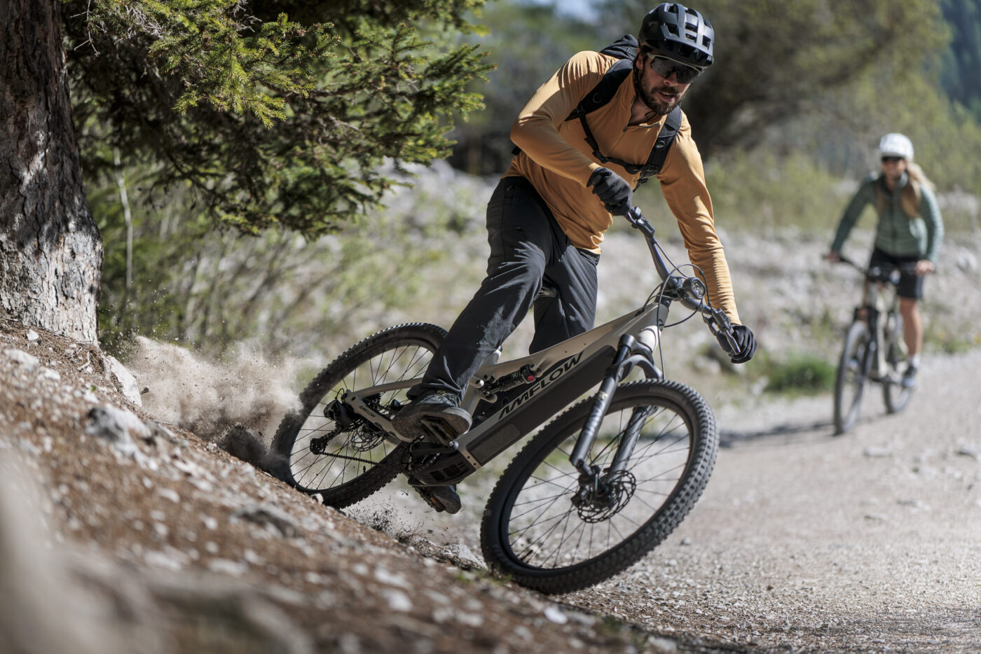 Mann fährt Amflow TL Carbon aggressiv in Schotterkurve, Frau folgt auf Trail