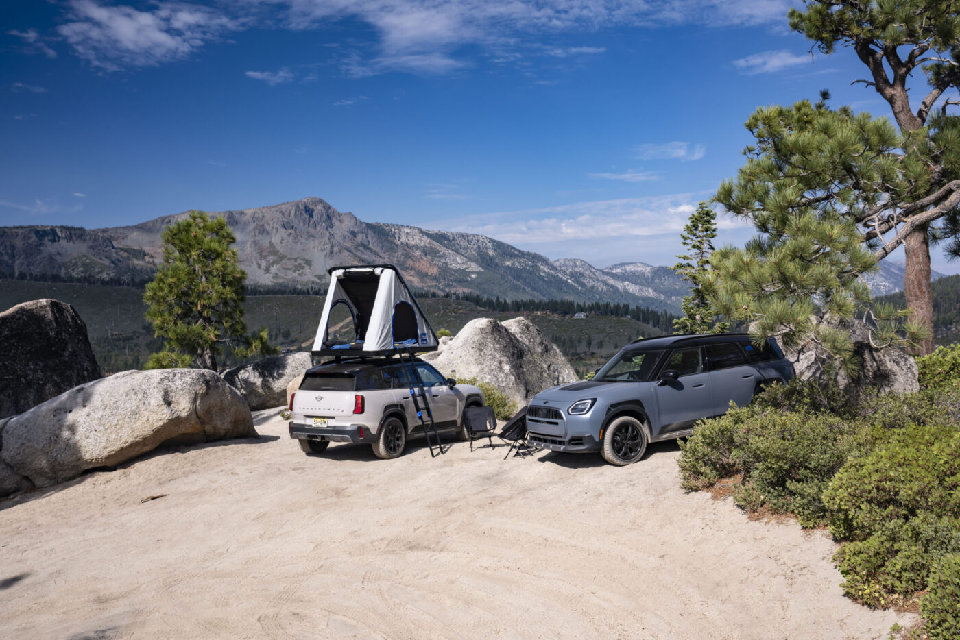 Zwei MINI Countryman Untamed Edition auf Felsplateau, einer mit geöffnetem Autohome-Dachzelt, Bergpanorama