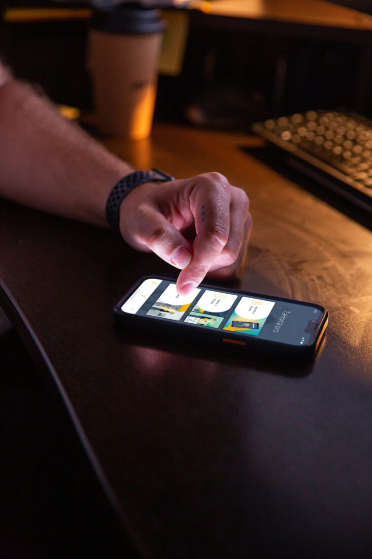 Hand bedient die Somfy TaHoma App auf einem Smartphone zur Rollladen-Steuerung