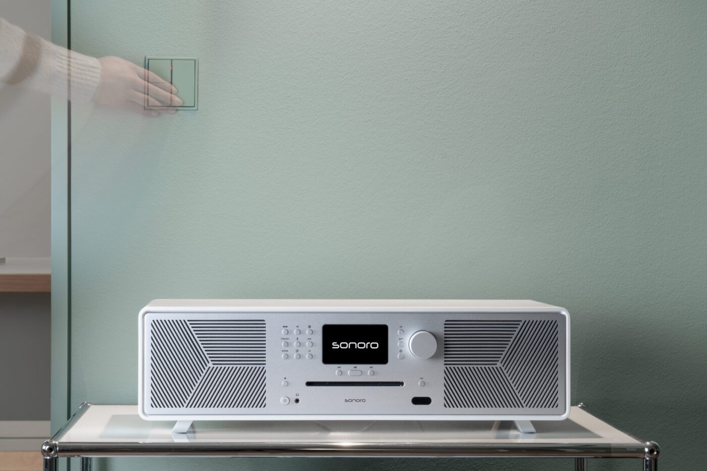 Sonoro MAESTRO Quantum auf Glasregal vor mintgrüner Wand, weiß-silbernes Gehäuse mit Display