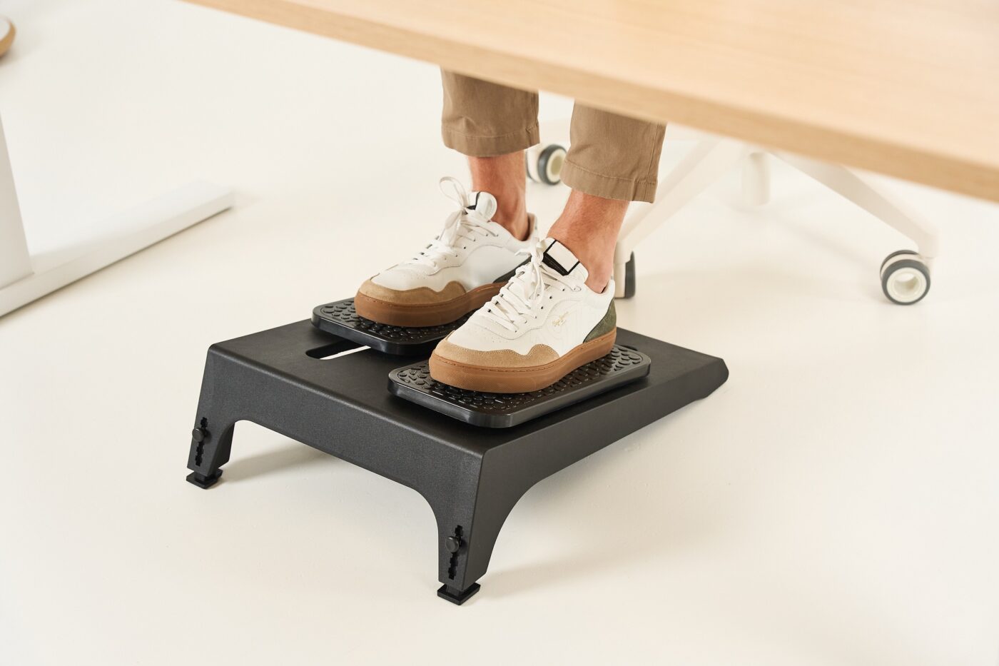 Füße in Sneakern auf dem Interstuhl MOVIQ Cross unter einem Schreibtisch