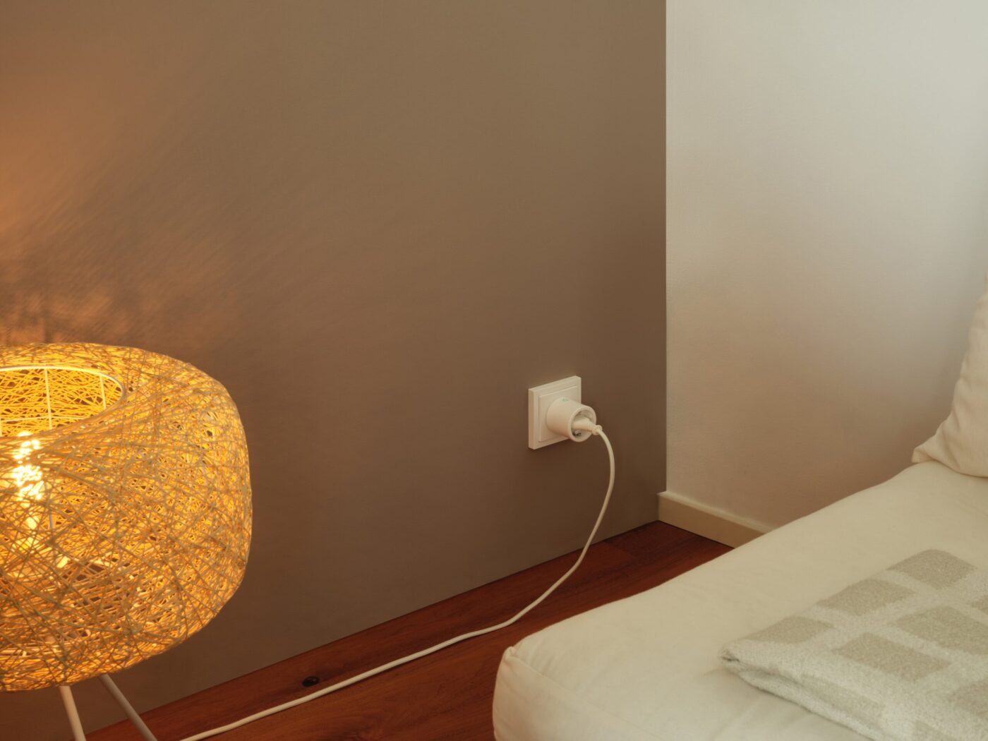 Smarte Zwischenstecker-Steckdose von OSRAM SMART+ an einer Wand neben einer Stehlampe