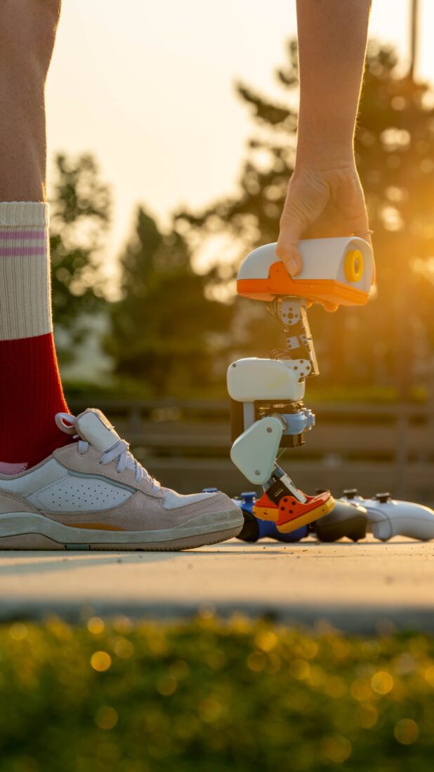 Microduck-Roboter auf Rollschuhen neben einem Fuß im Sneaker auf einem Weg im Abendlicht