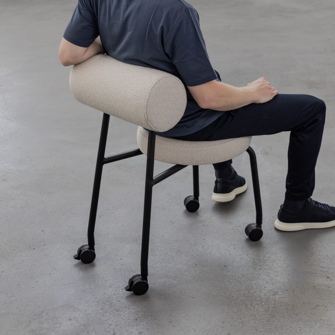 Mann lehnt sich an die gepolsterte Rolle eines Studiotools HighLow Chair