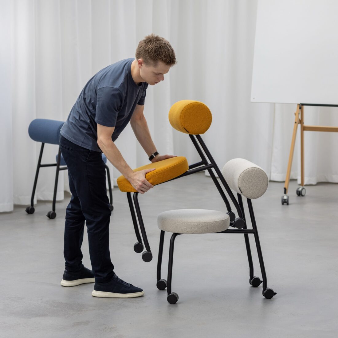 Mann klappt die Rückenlehne eines Studiotools HighLow Chair nach vorn