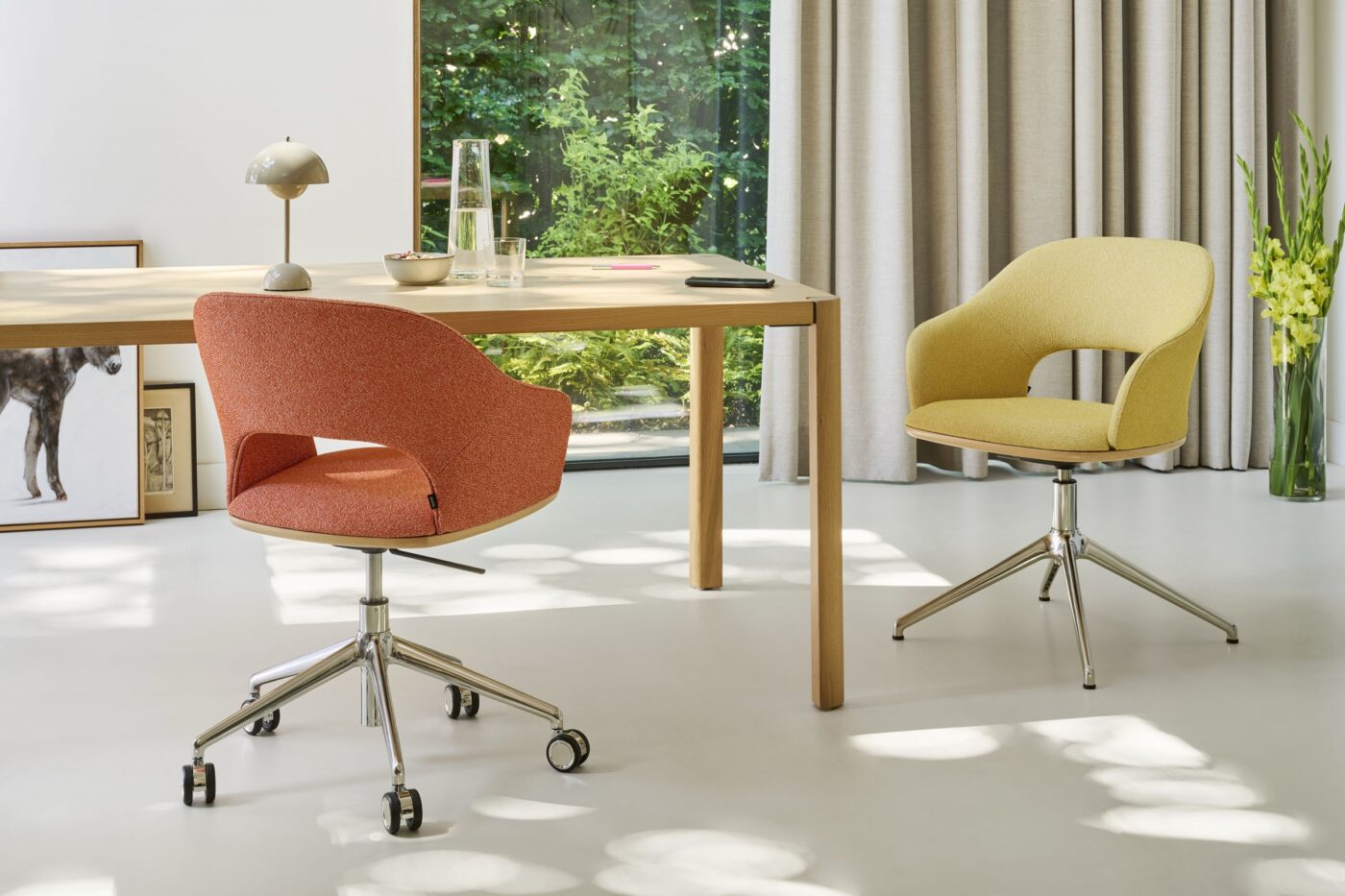 Zwei Thonet-Drehsessel 521 in Koralle und Gelb an einem Holztisch in einem hellen Raum