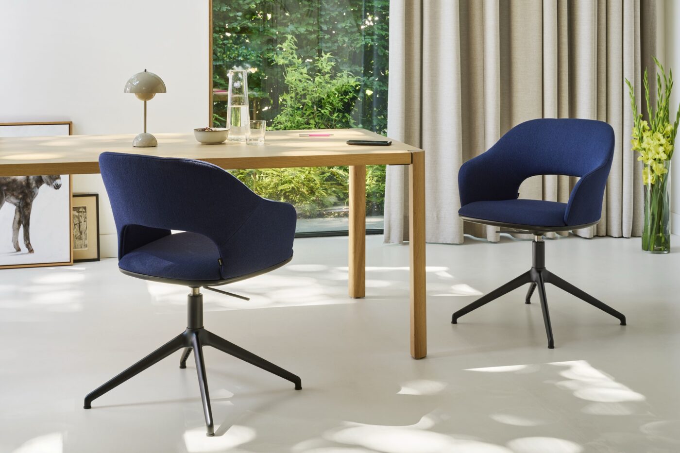 Zwei dunkelblaue Thonet-Drehsessel 521 mit schwarzem Vierarmgestell an einem Holztisch